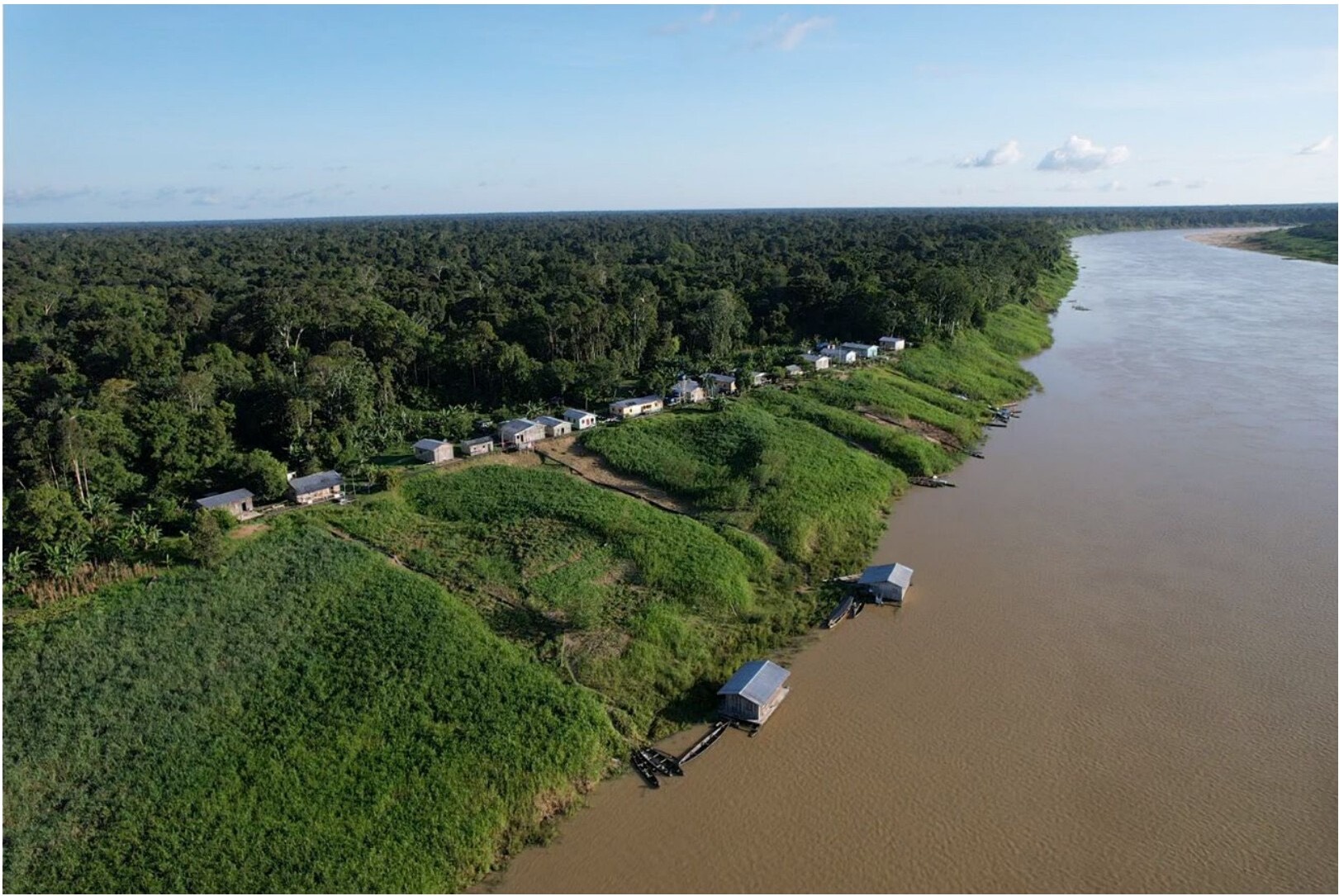 Aerial photograph of Vila São João on the Juruá river, in Ipixuna, Amazonas: rainforest to the horizon, the river that is the only way in, and the riverside community living on the bank.